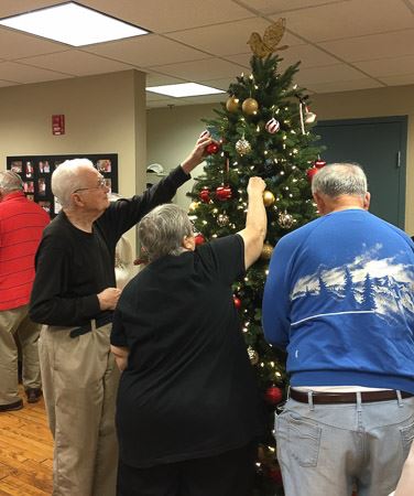 People Hanging Ornaments on Tree