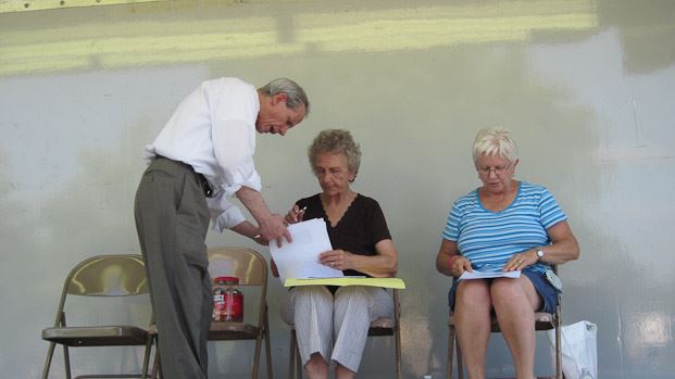 Man Explaining to Women Filling Out Paperwork